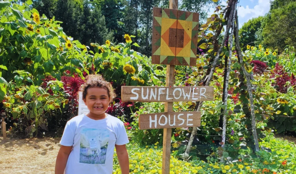 a person standing in front of a sign that says sunflower house