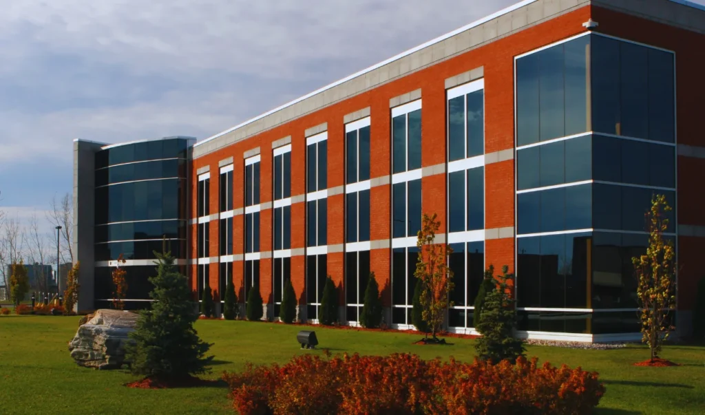 a large building with lots of windows on the side of a grassy field