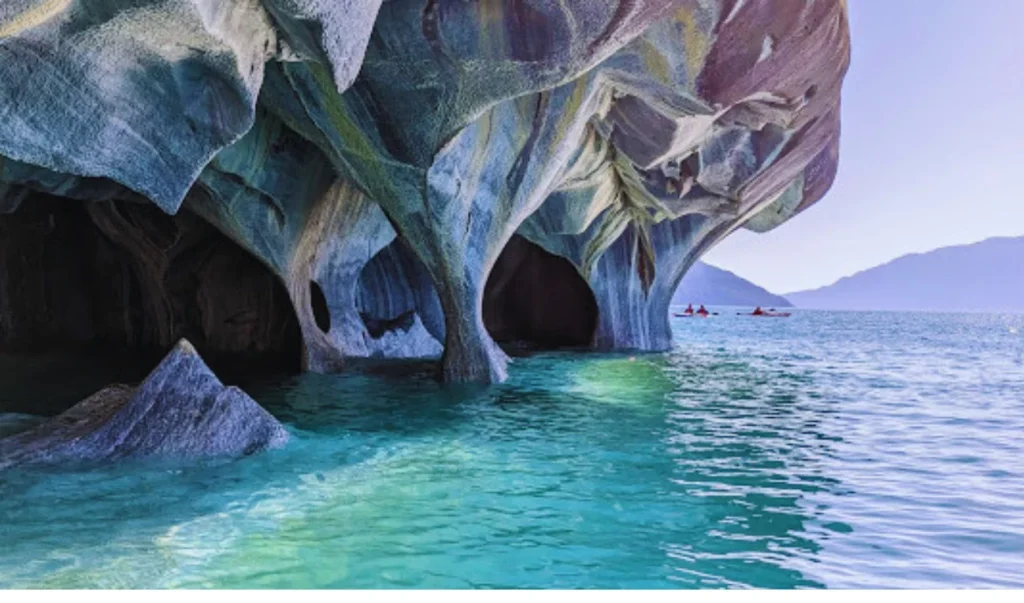 an image of a cave in the ocean with boats in the water