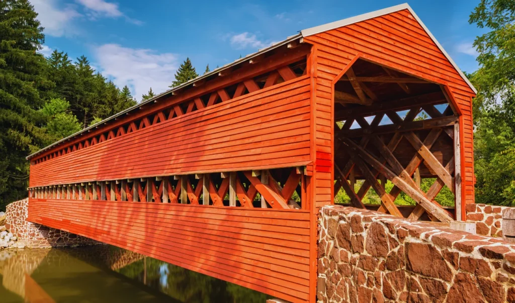 a red covered bridge crosses over a body of water