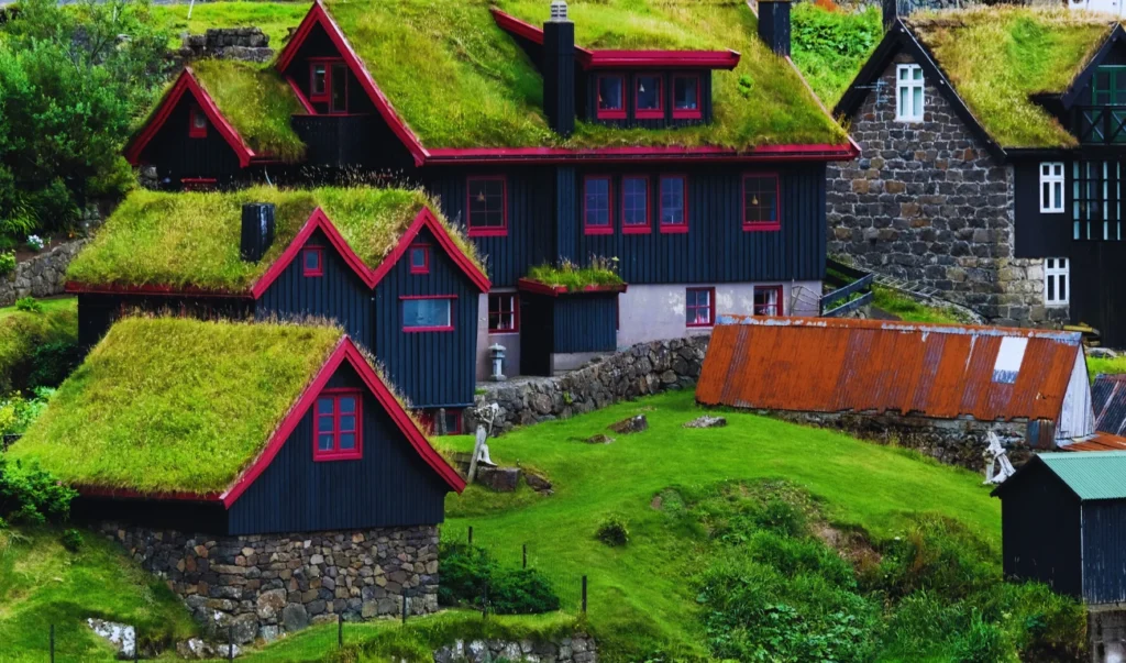 a group of houses with grass roofs on top of a hill