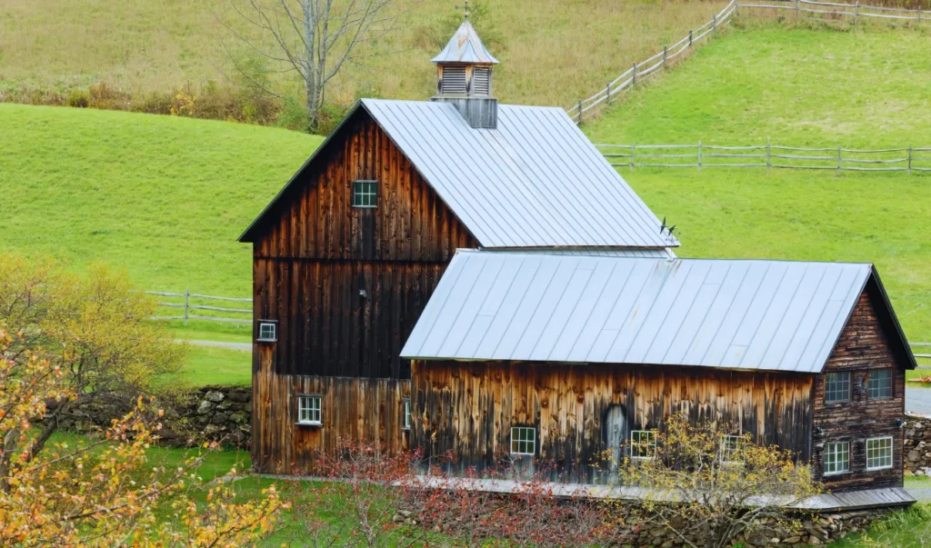 an old wooden barn sits in the middle of a green field